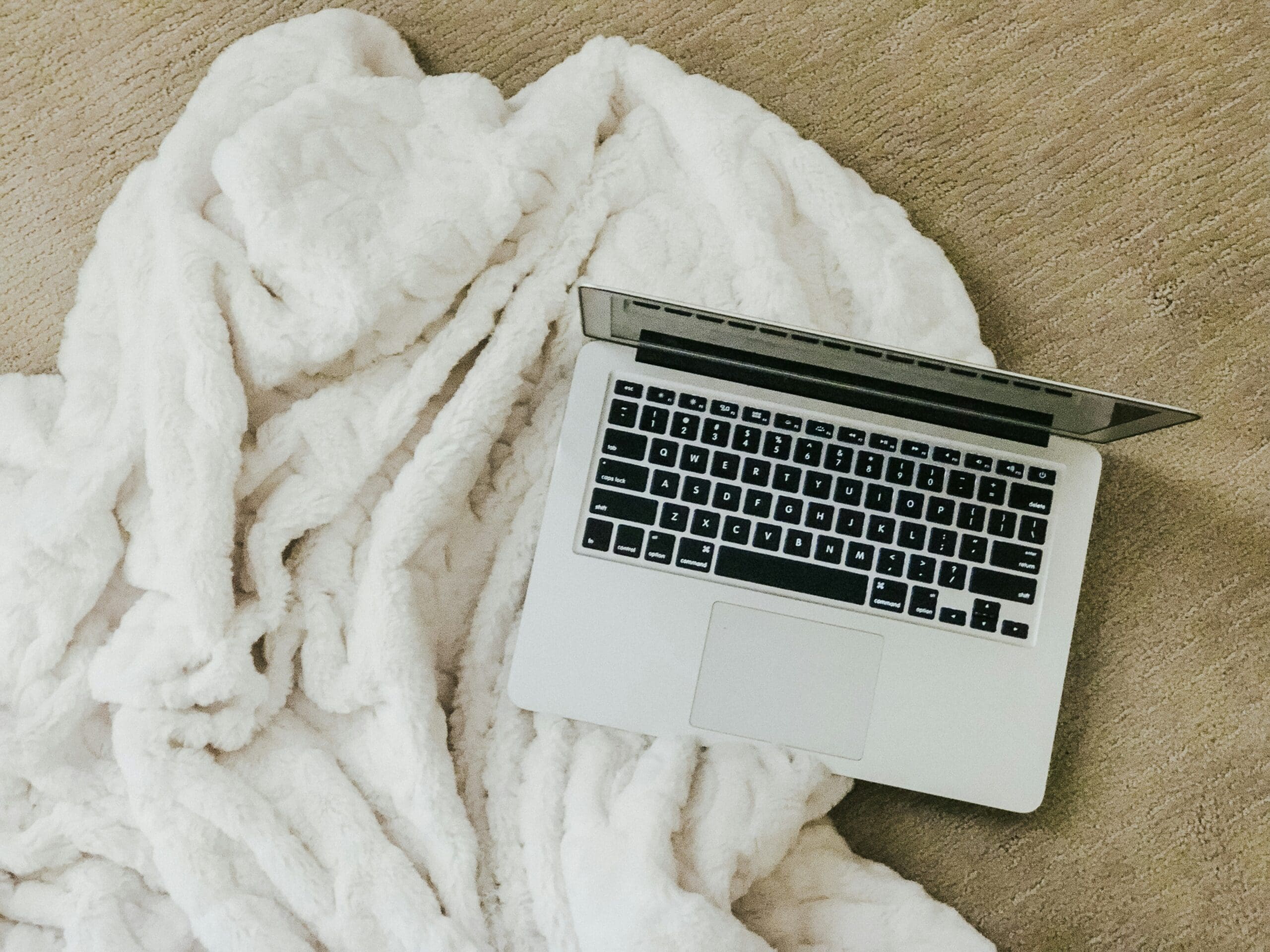 Laptop next to cozy blanket