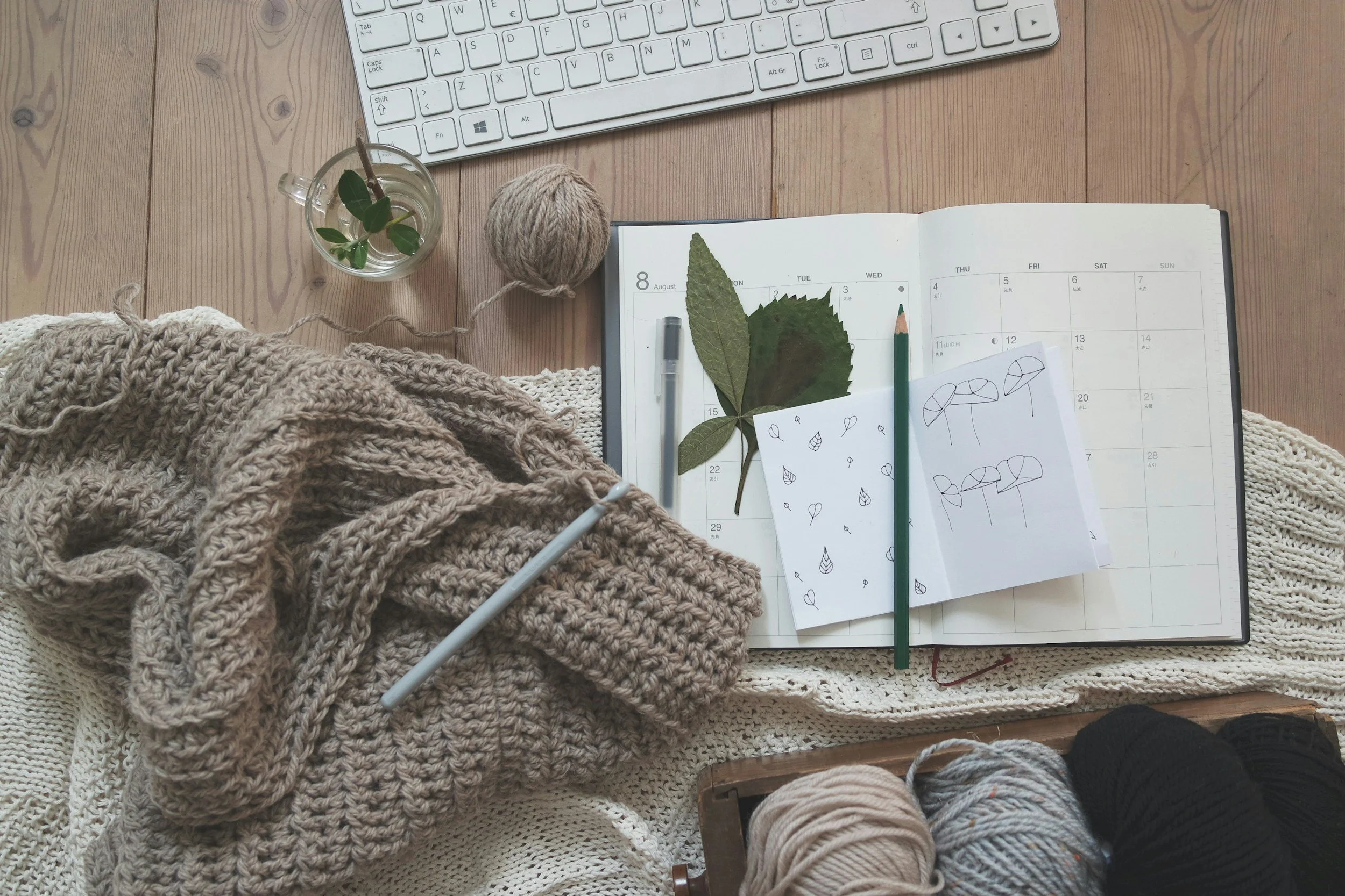 Open planner on a desk with cozy fabrics and a plant.