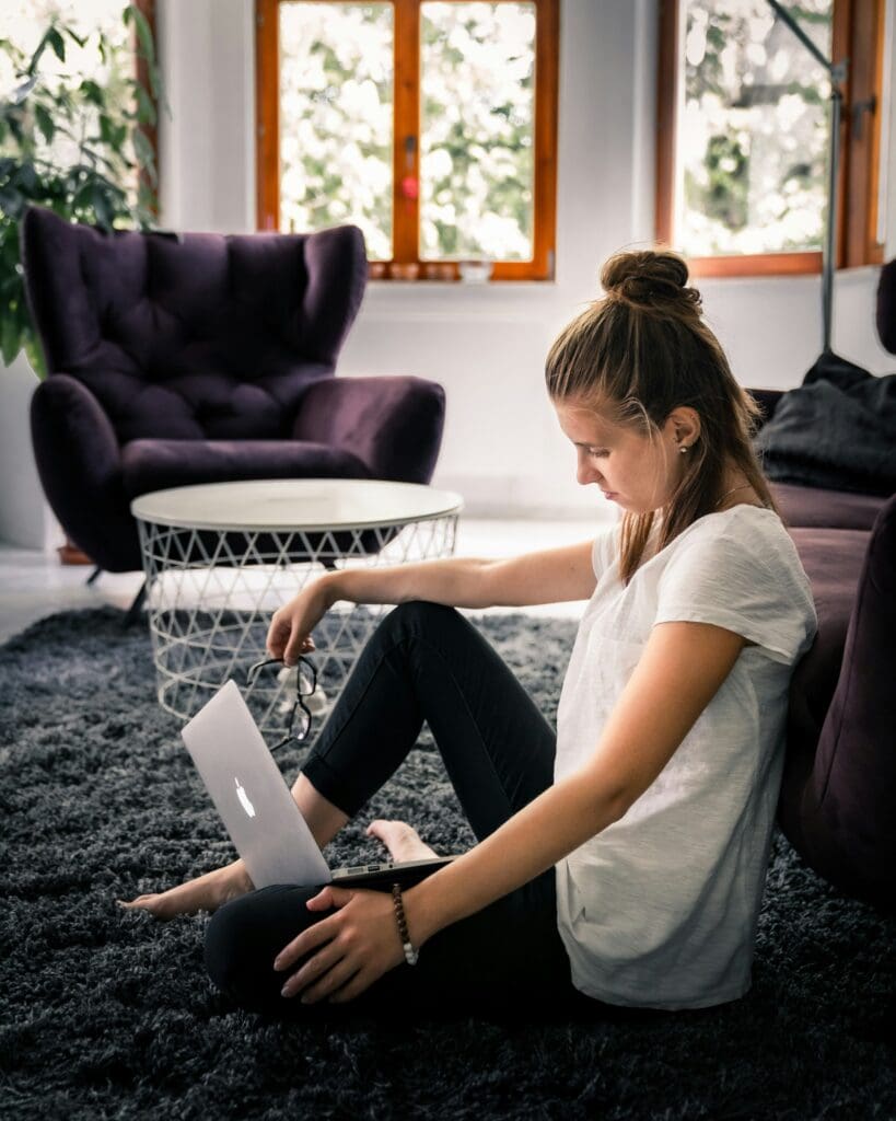woman in loungewear sitting on floor with laptop
