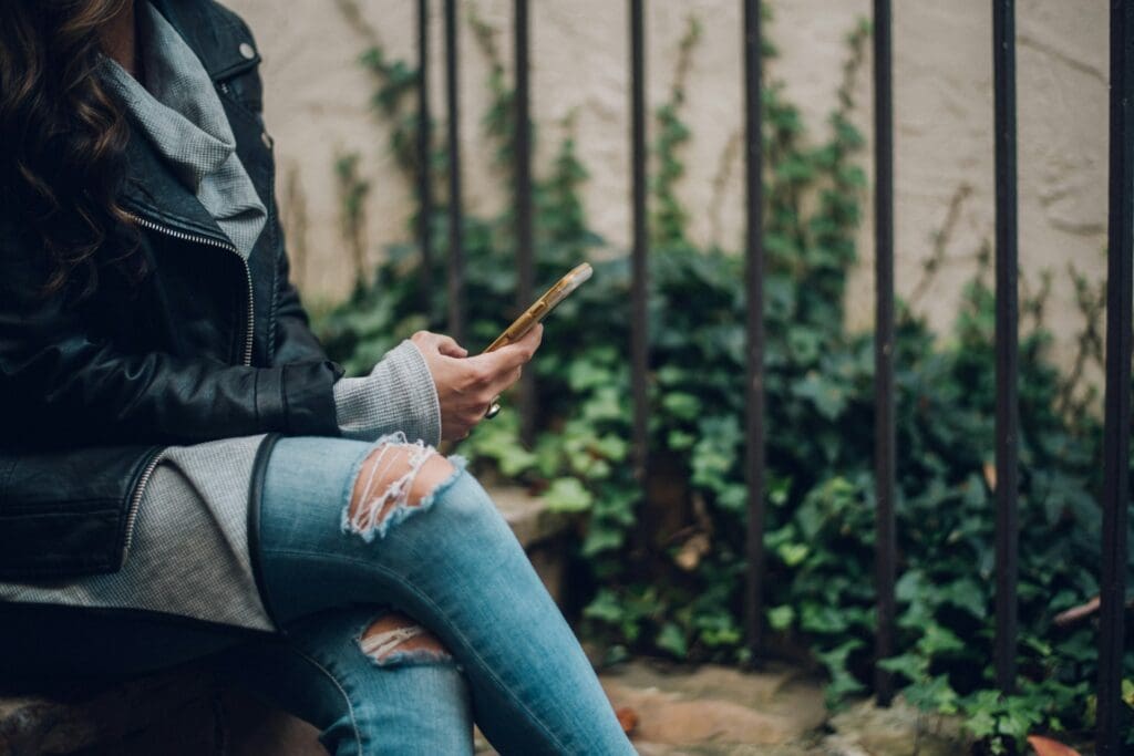 woman sitting on stairs while looking on her phone